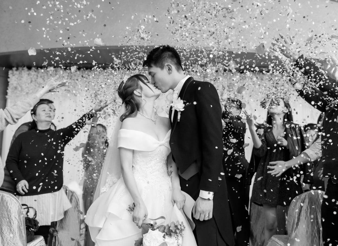 Newlyweds walking through a shower of confetti thrown by their guests